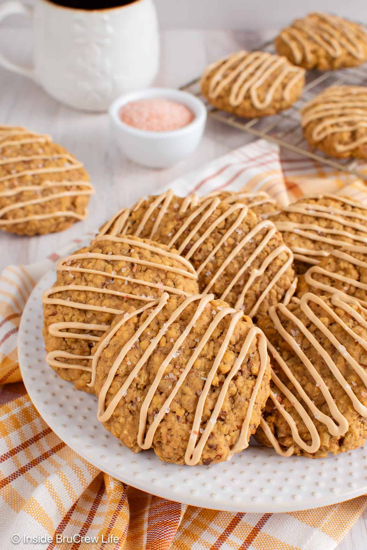 Pumpkin pecan cookies with a coffee glaze drizzle stacked on a white plate.