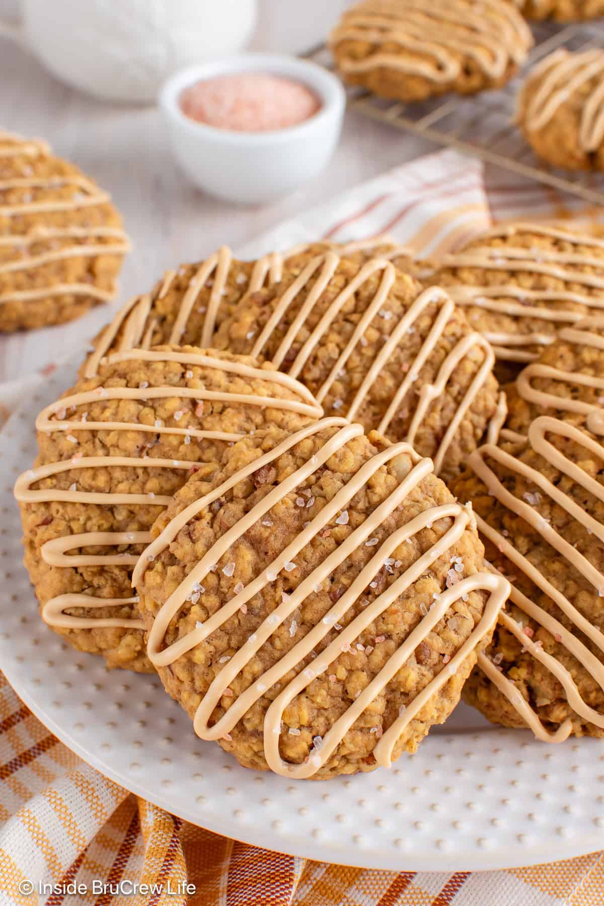 Pumpkin pecan cookies with a coffee glaze stacked on a white plate.