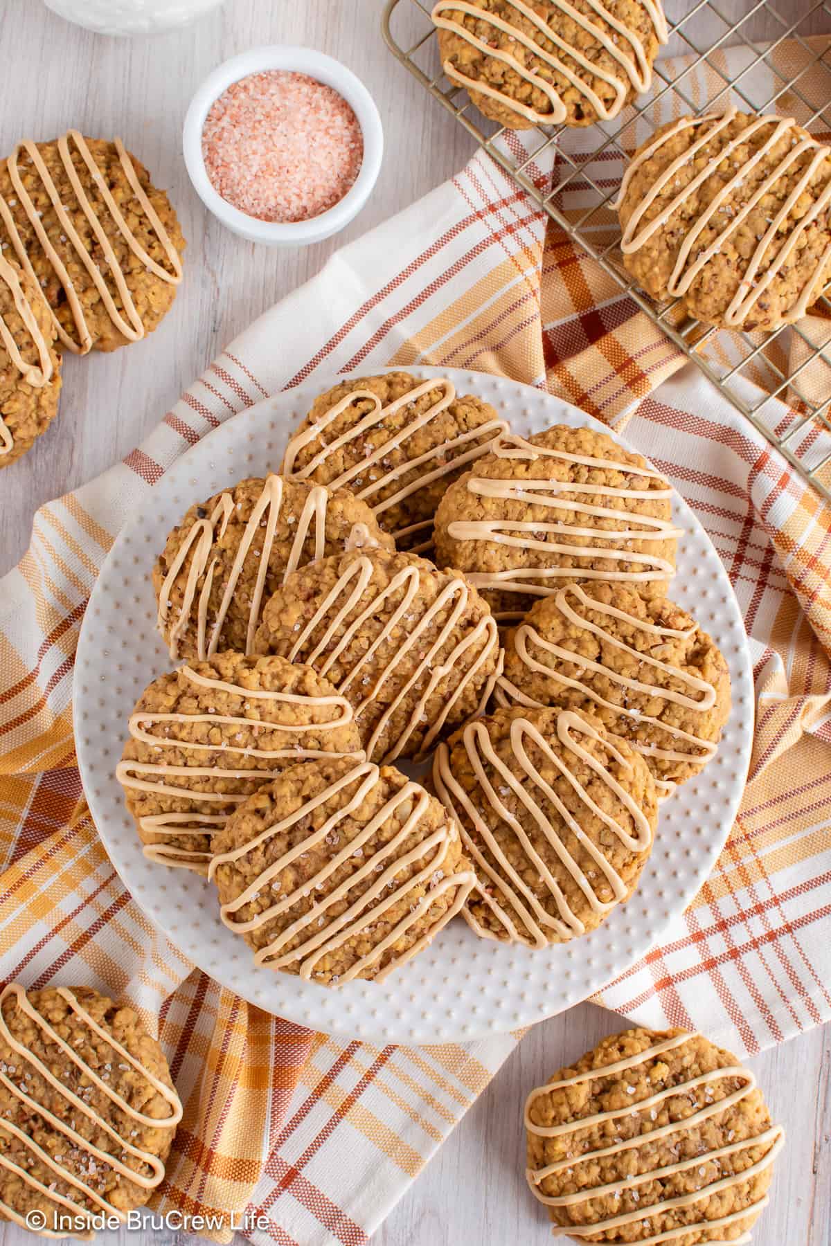 An overhead picture of pumpkin cookies on a white plate with more around it.