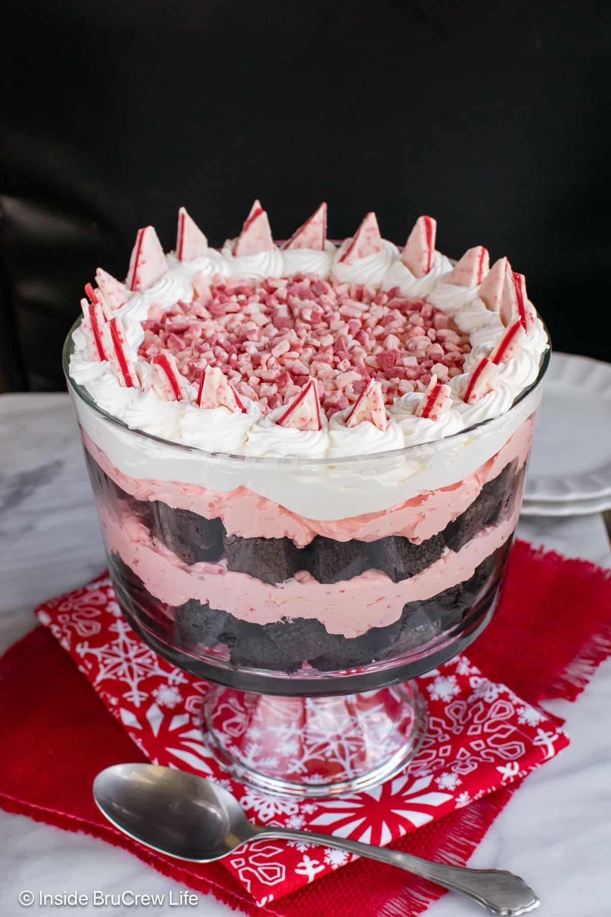 Layers of brownie chunks and peppermint cheesecake layered in a glass trifle bowl.