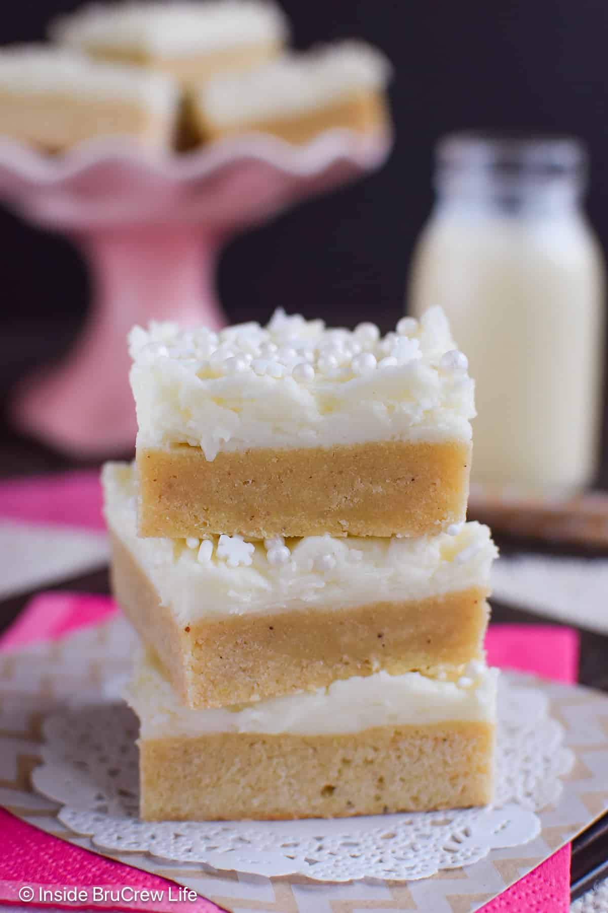 A stack of three frosted eggnog cookie bars on a white paper.