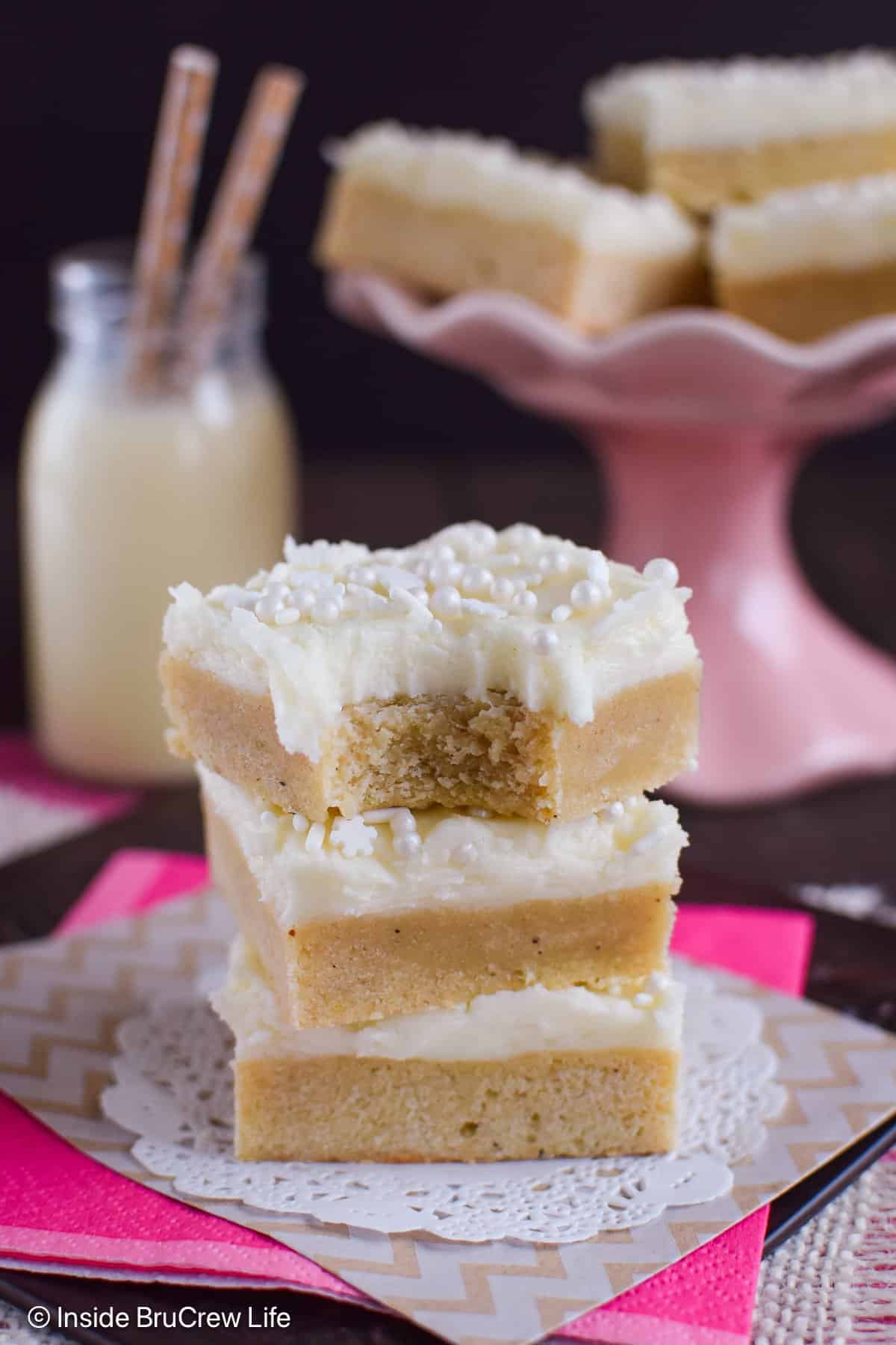 A stack of frosted eggnog bars with a bite out of the top bar.