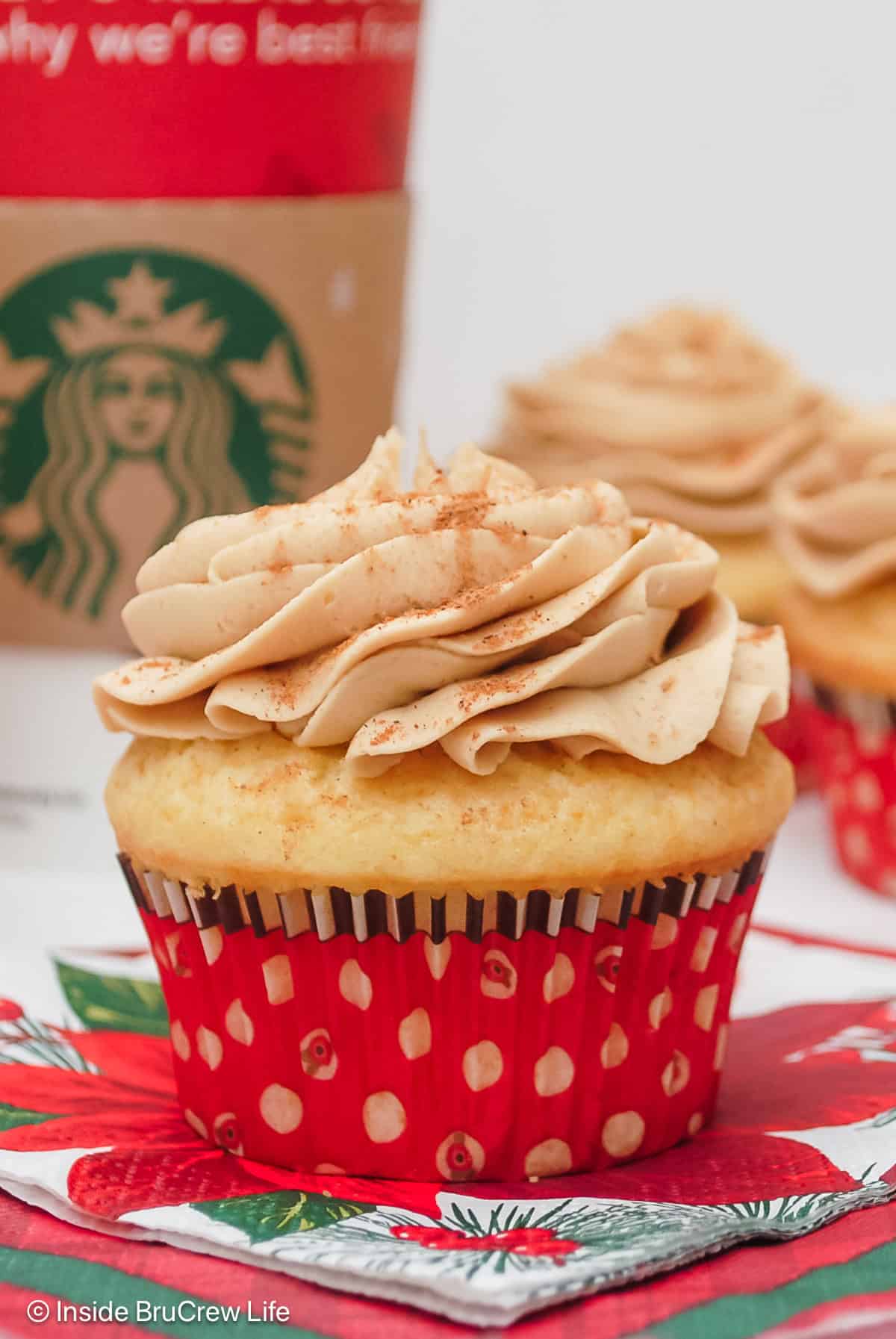 Two eggnog latte cupcakes with frosting in red liners.