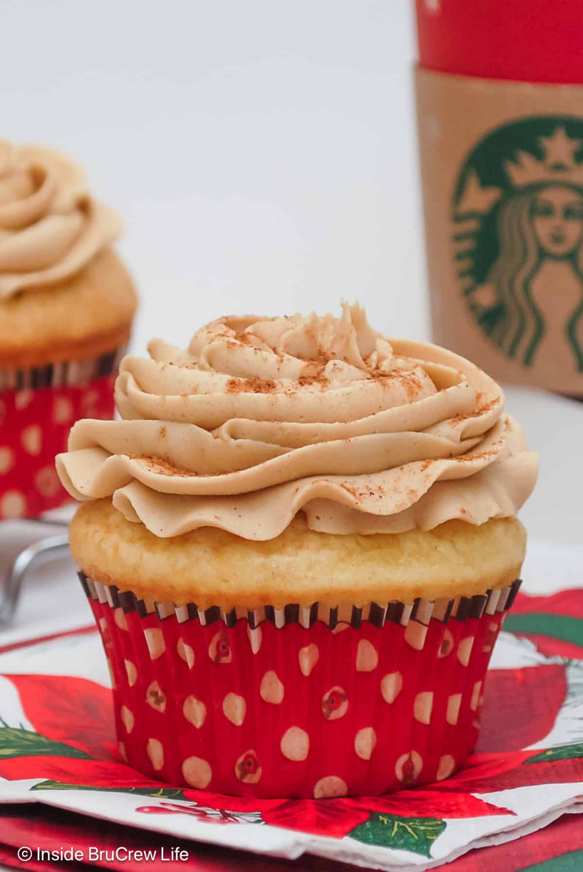 Two frosted eggnog cupcakes in red liners.