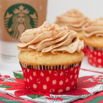 Two eggnog latte cupcakes with frosting in red liners.