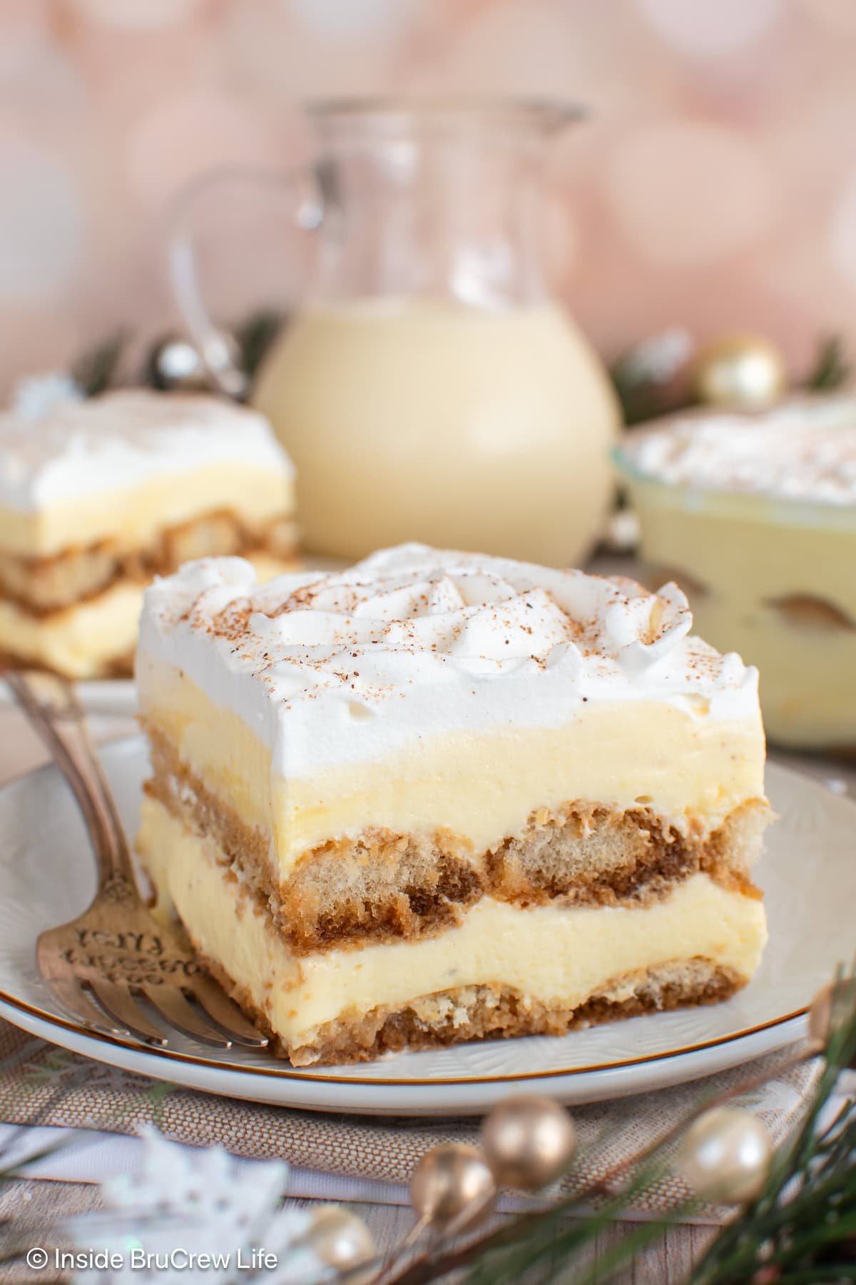 A large square of eggnog tiramisu on a plate with a fork.