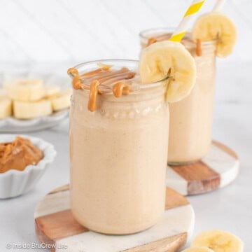 Two cups filled with a peanut butter and banana smoothie, then topped with extra peanut butter.