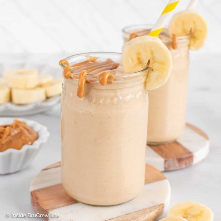 Two cups filled with a peanut butter and banana smoothie, then topped with extra peanut butter.