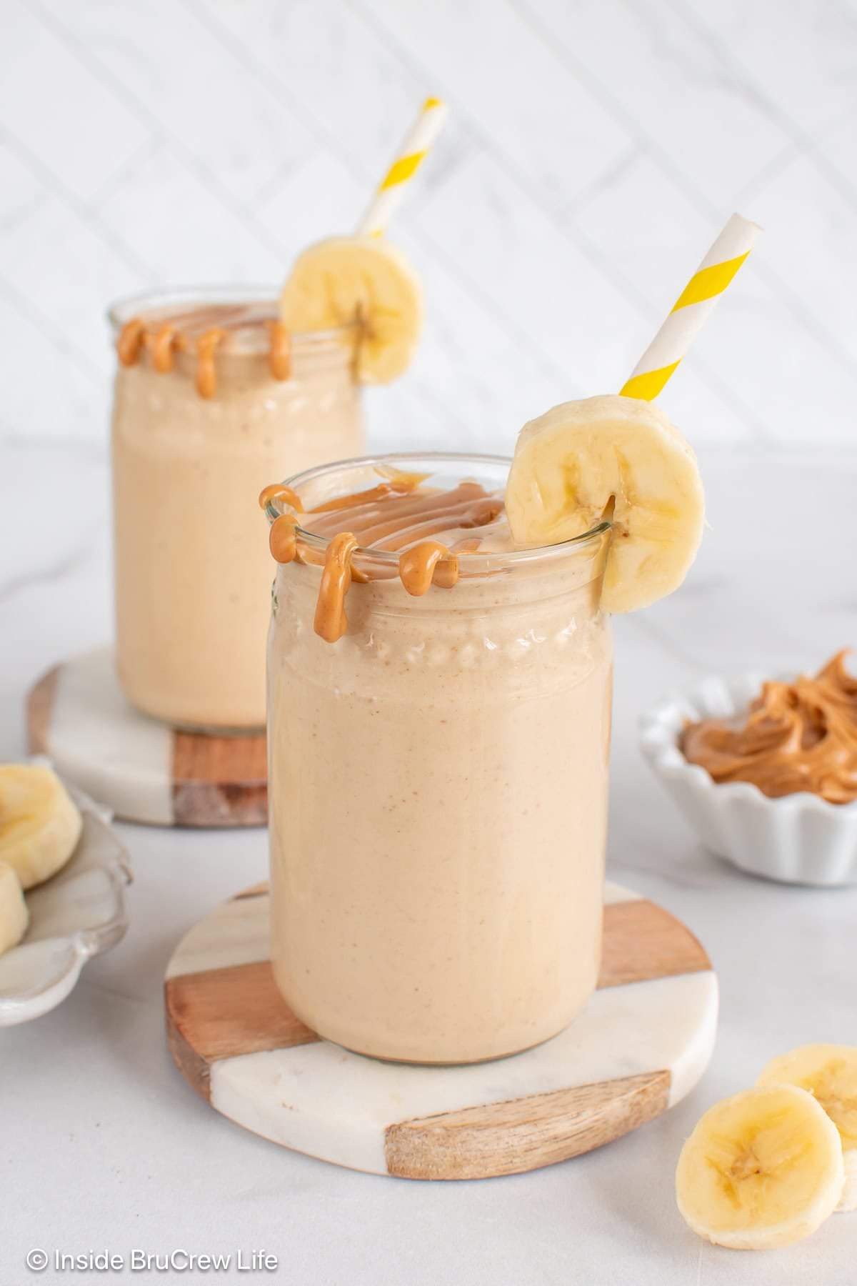 Two cups filled with a peanut butter and banana smoothie, then topped with extra peanut butter.