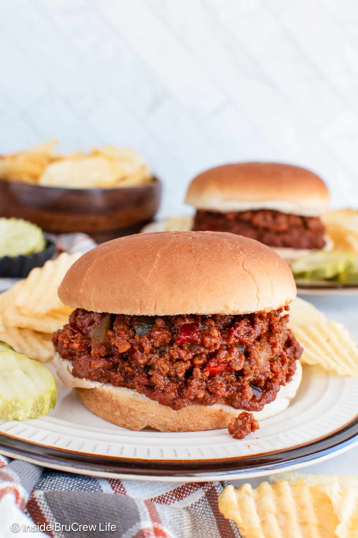 Two plates with hamburger buns filled with sloppy joes.