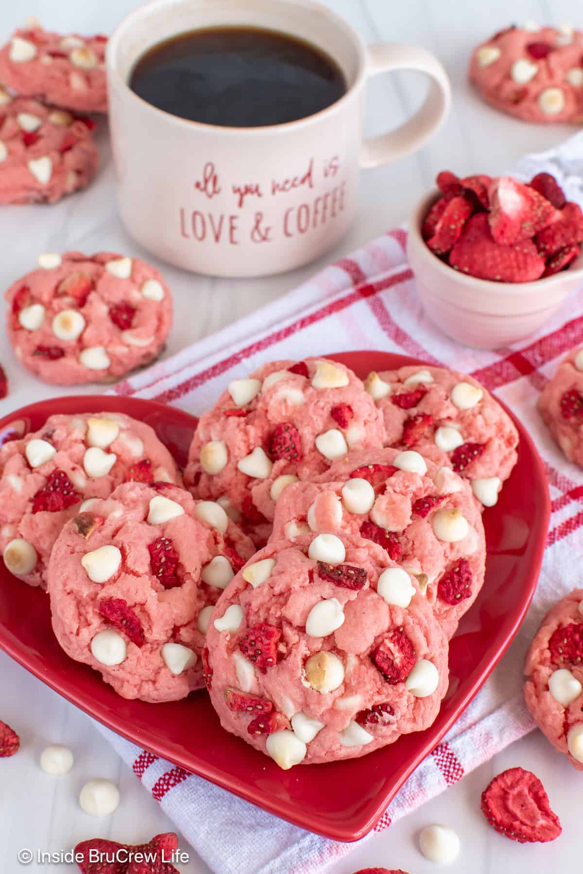 A plate of strawberry cake mix cookies with a cup of coffee behind it.