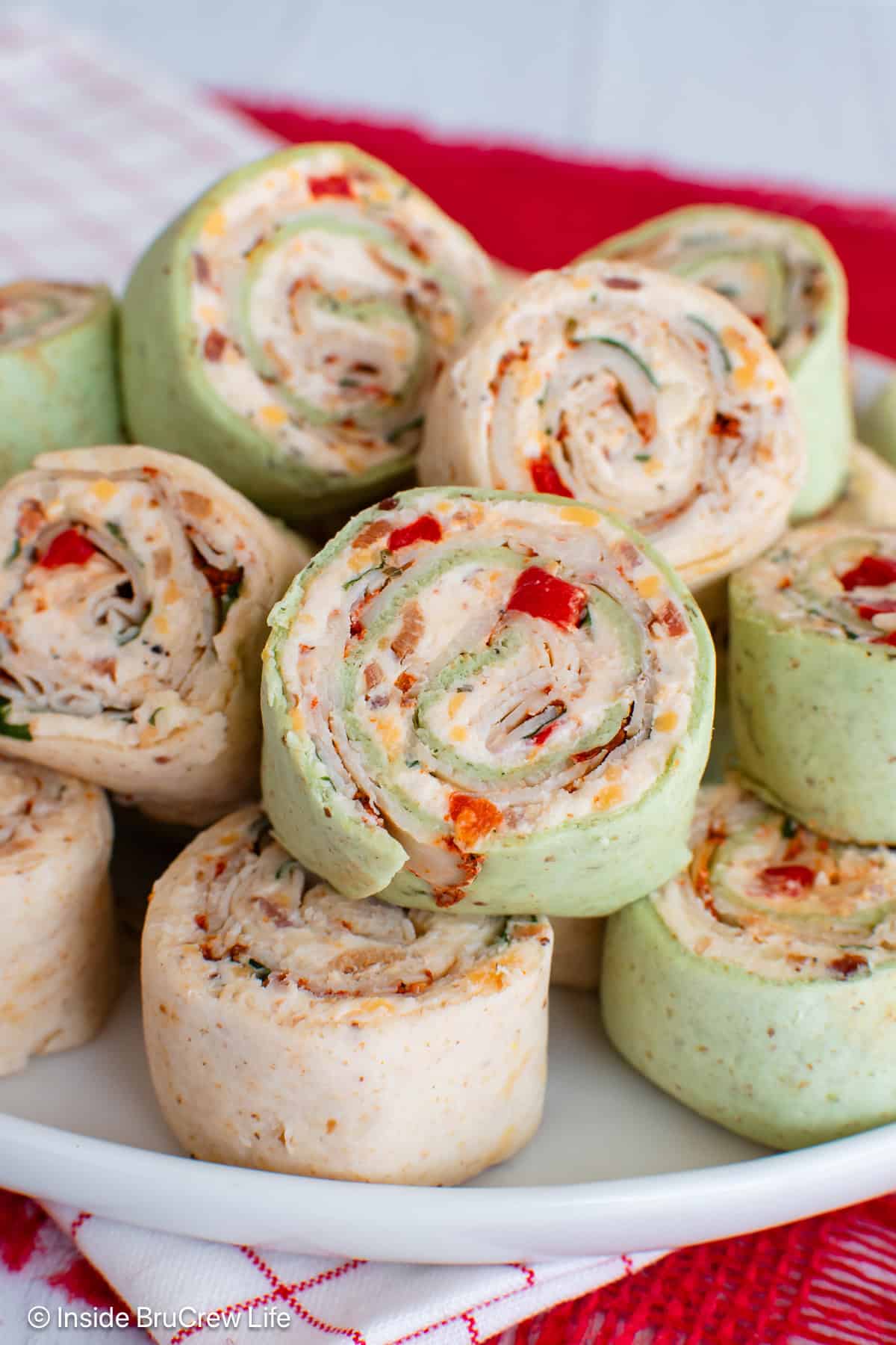 Creamy turkey pinwheels stacked on a plate.