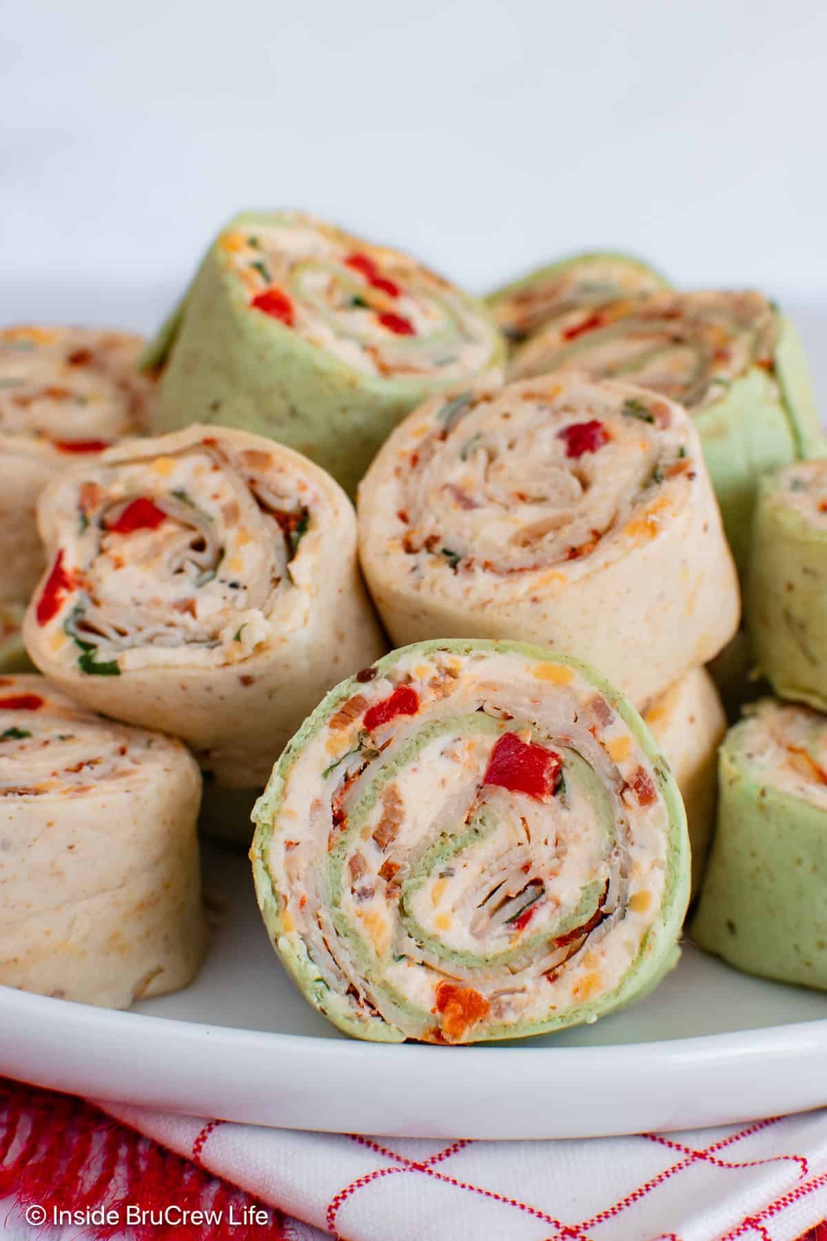 A stack of turkey cheese pinwheels on a white plate.