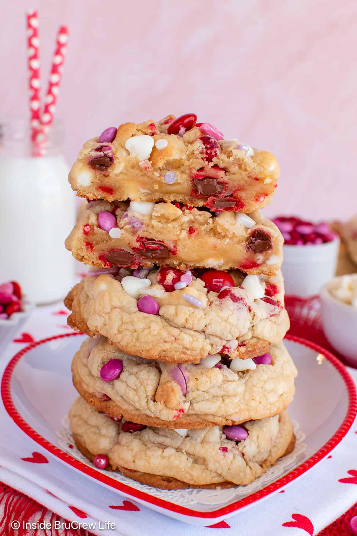 A stack of Valentine's chocolate chip cookies on a plate with the top cookie cut in half.