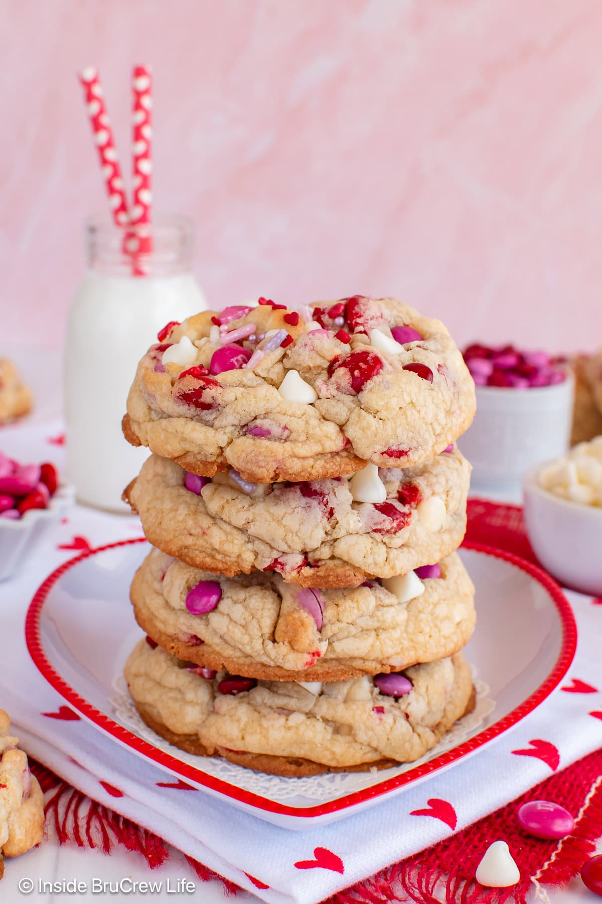 Four Valentine's M&M cookies stacked on a plate.