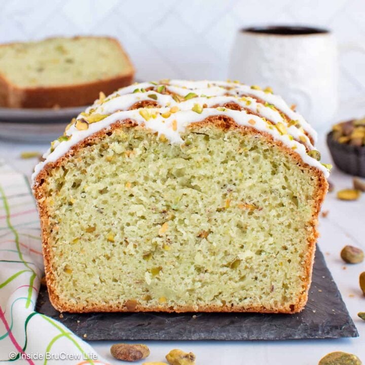 A sliced loaf of pistachio bread standing on a slate board.