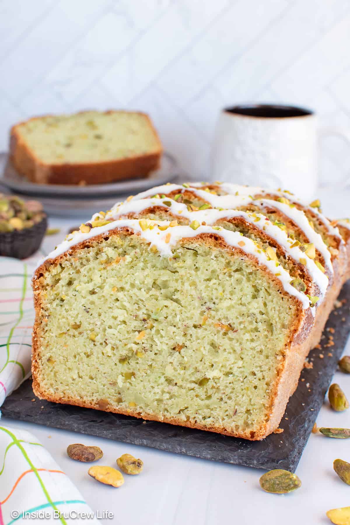 Slices of frosted pistachio bread on a slate board.