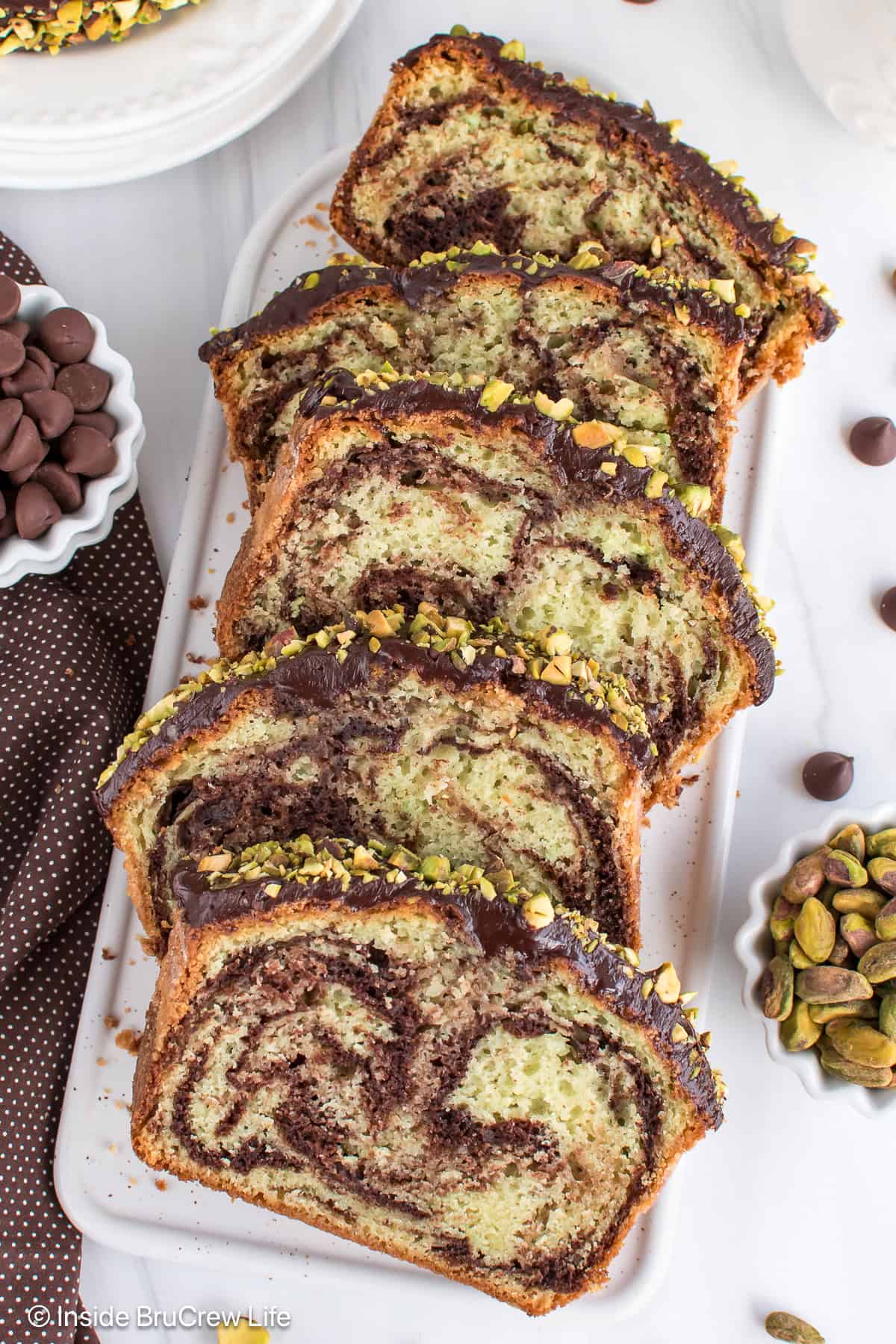Overhead picture of a sliced chocolate pistachio loaf on a white plate.