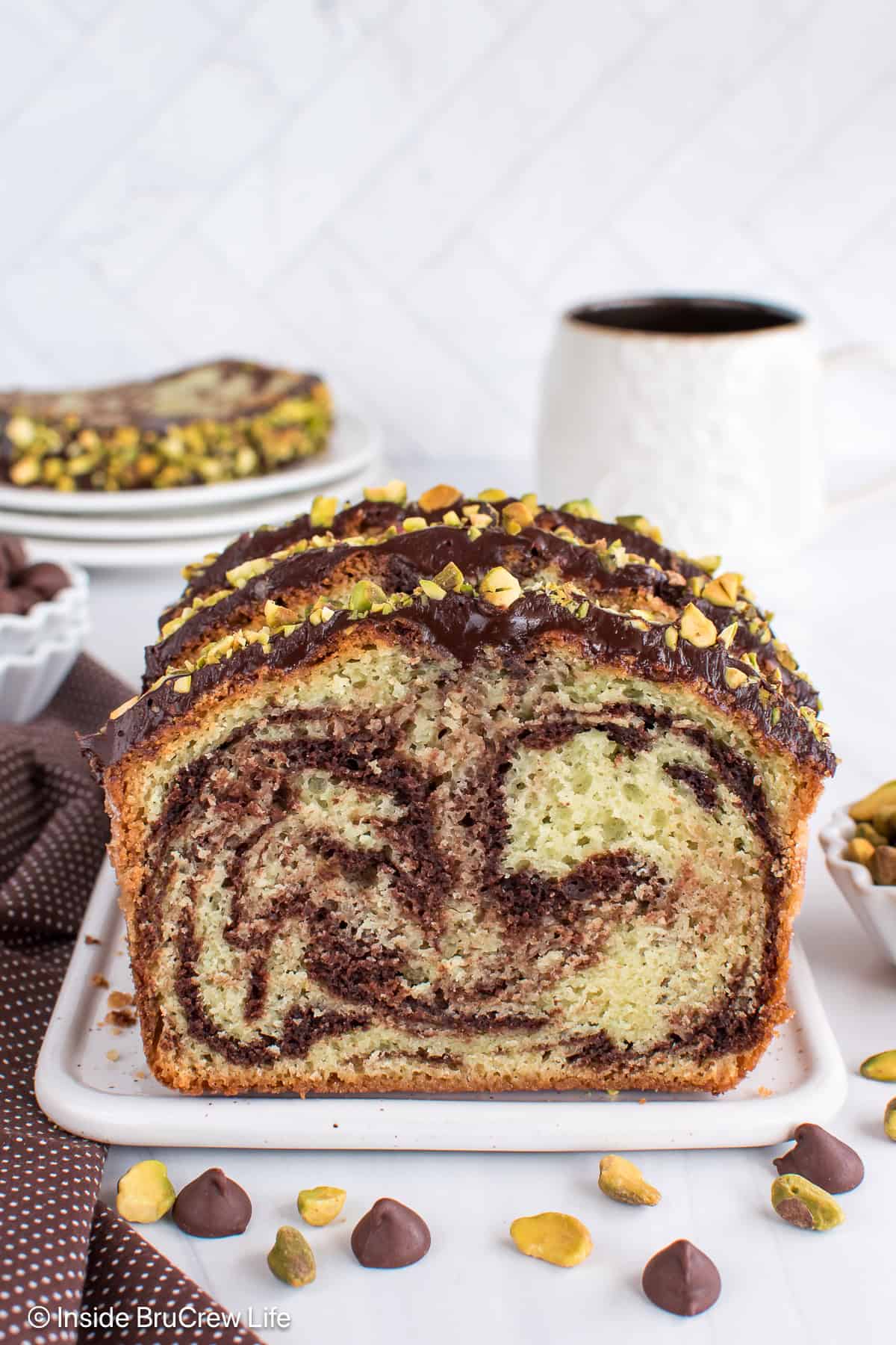Swirled chocolate pistachio loaf slices on a white tray.