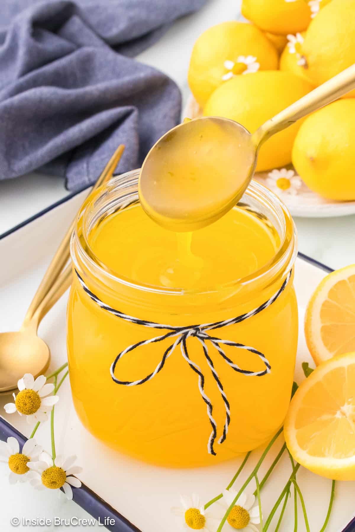 A jar of warm lemon pie filling with a spoon pouring some in.