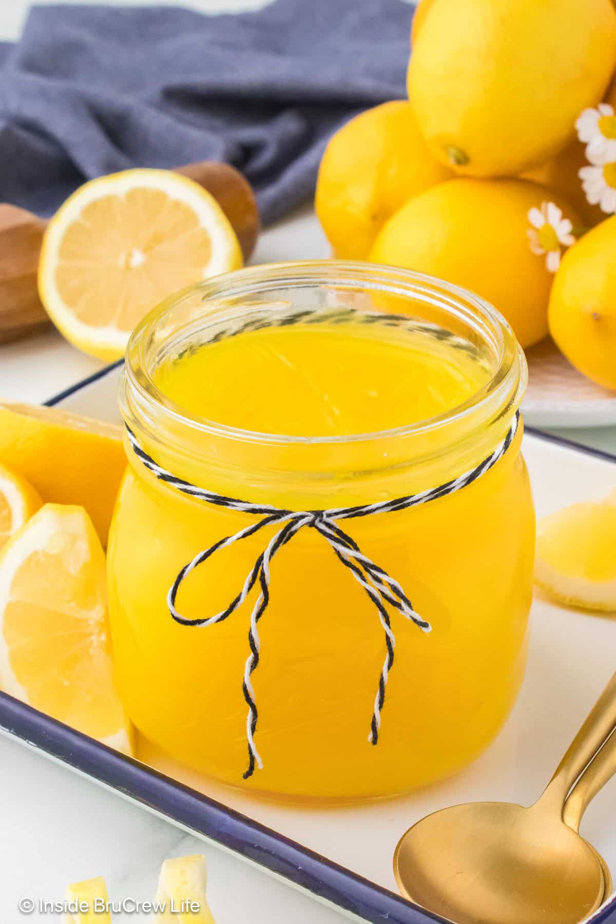 A jar of lemon pie filling with lemons all around it.