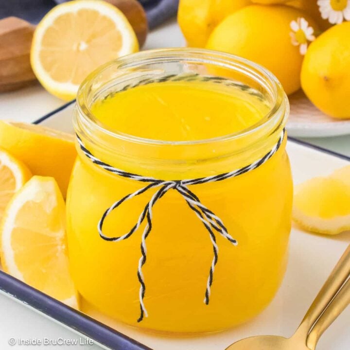 A jar of lemon pie filling with lemons all around it.