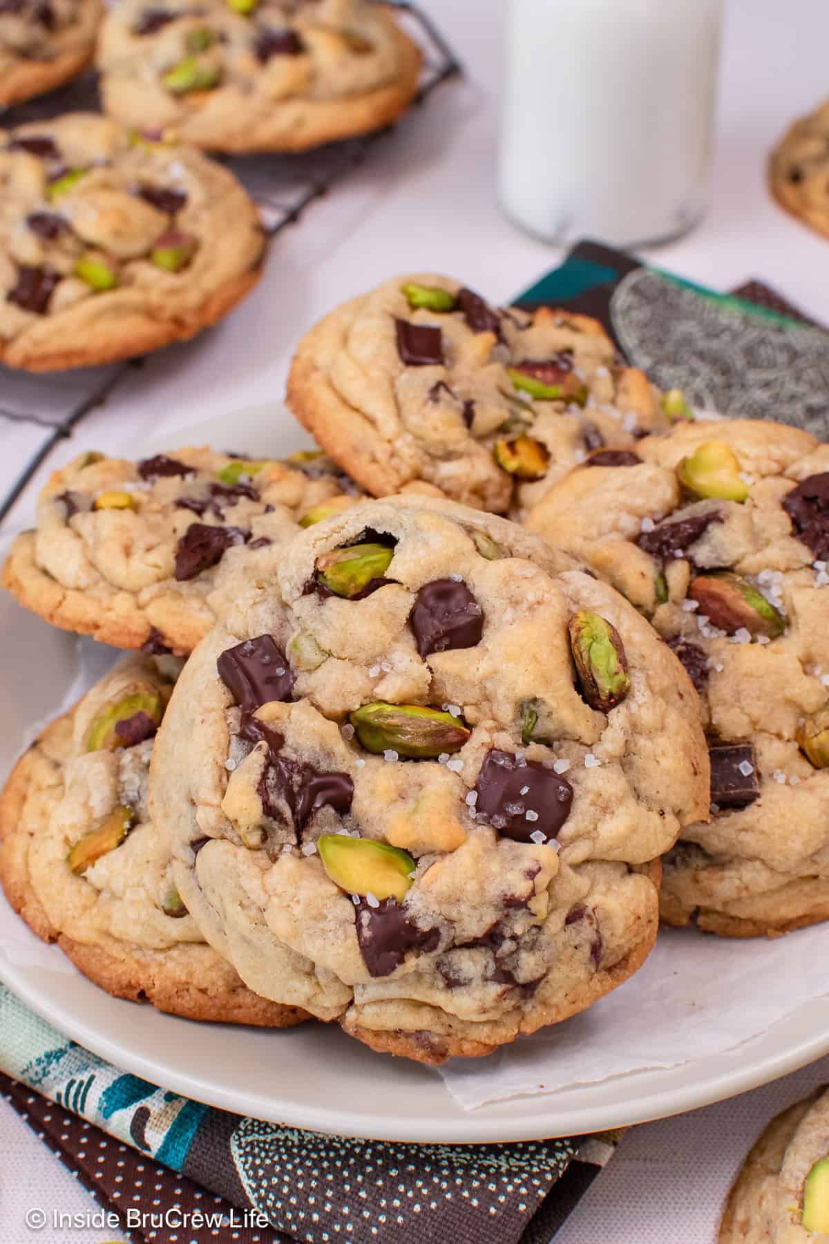Pistachio toffee chocolate chip cookies piled on a white plate.