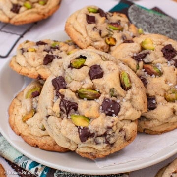 Pistachio toffee chocolate chip cookies piled on a white plate.