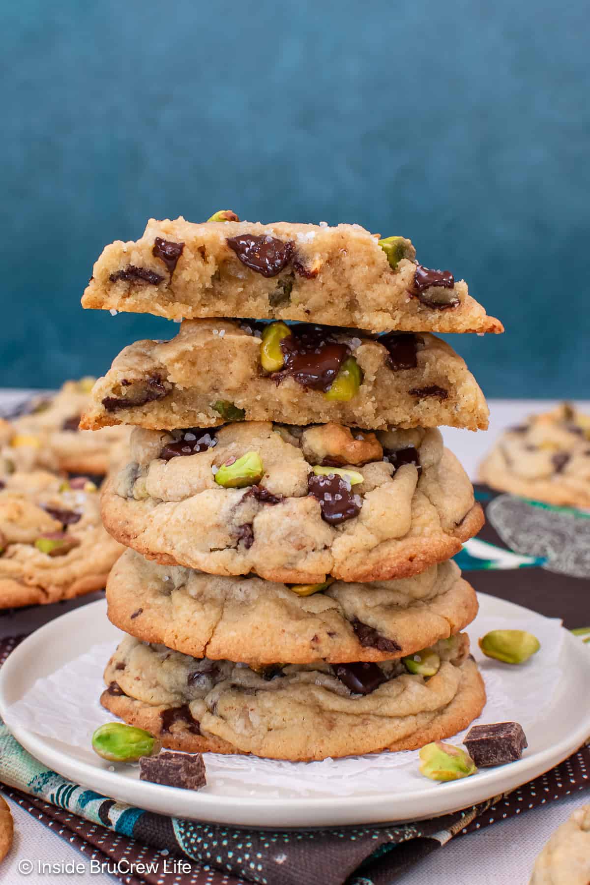 A stack of four pistachio toffee cookies with the top one cut in half.