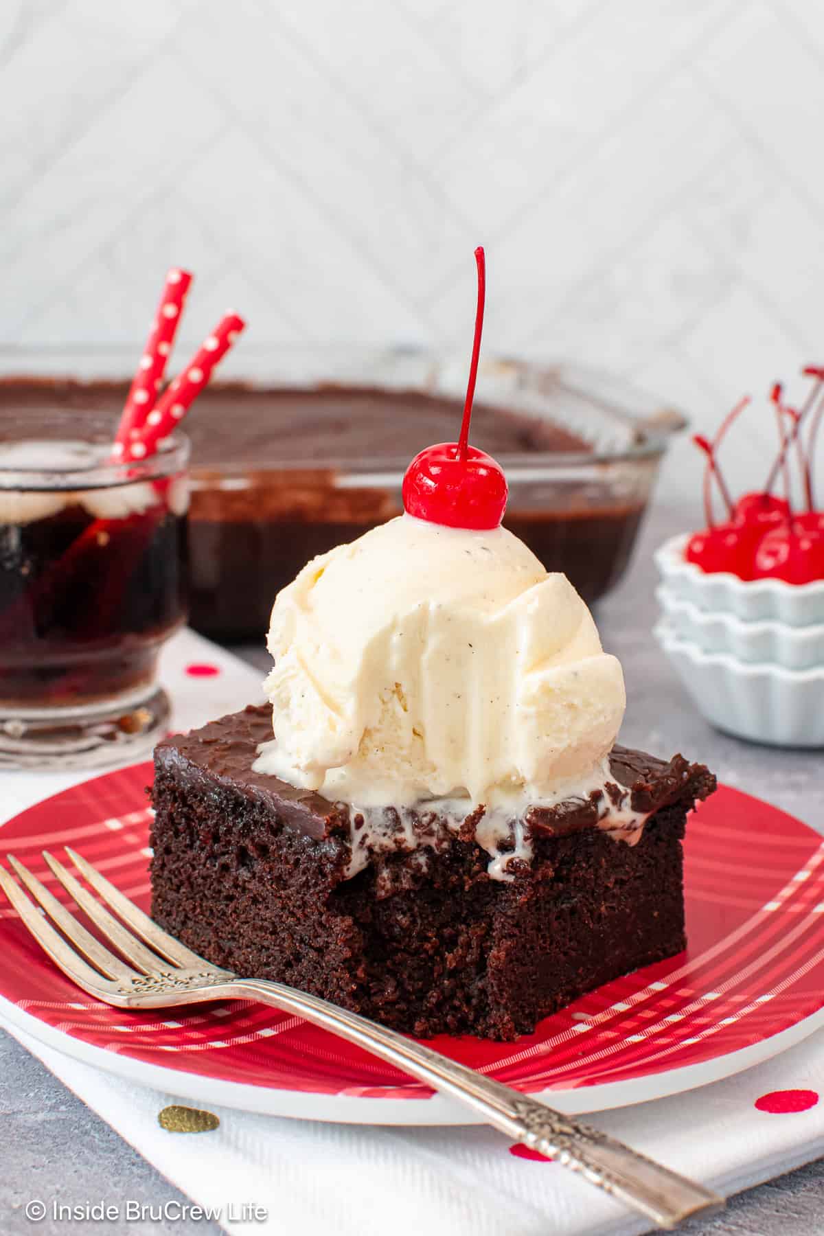 A piece of chocolate cola cake with ice cream and a bite taken out of it with a fork.