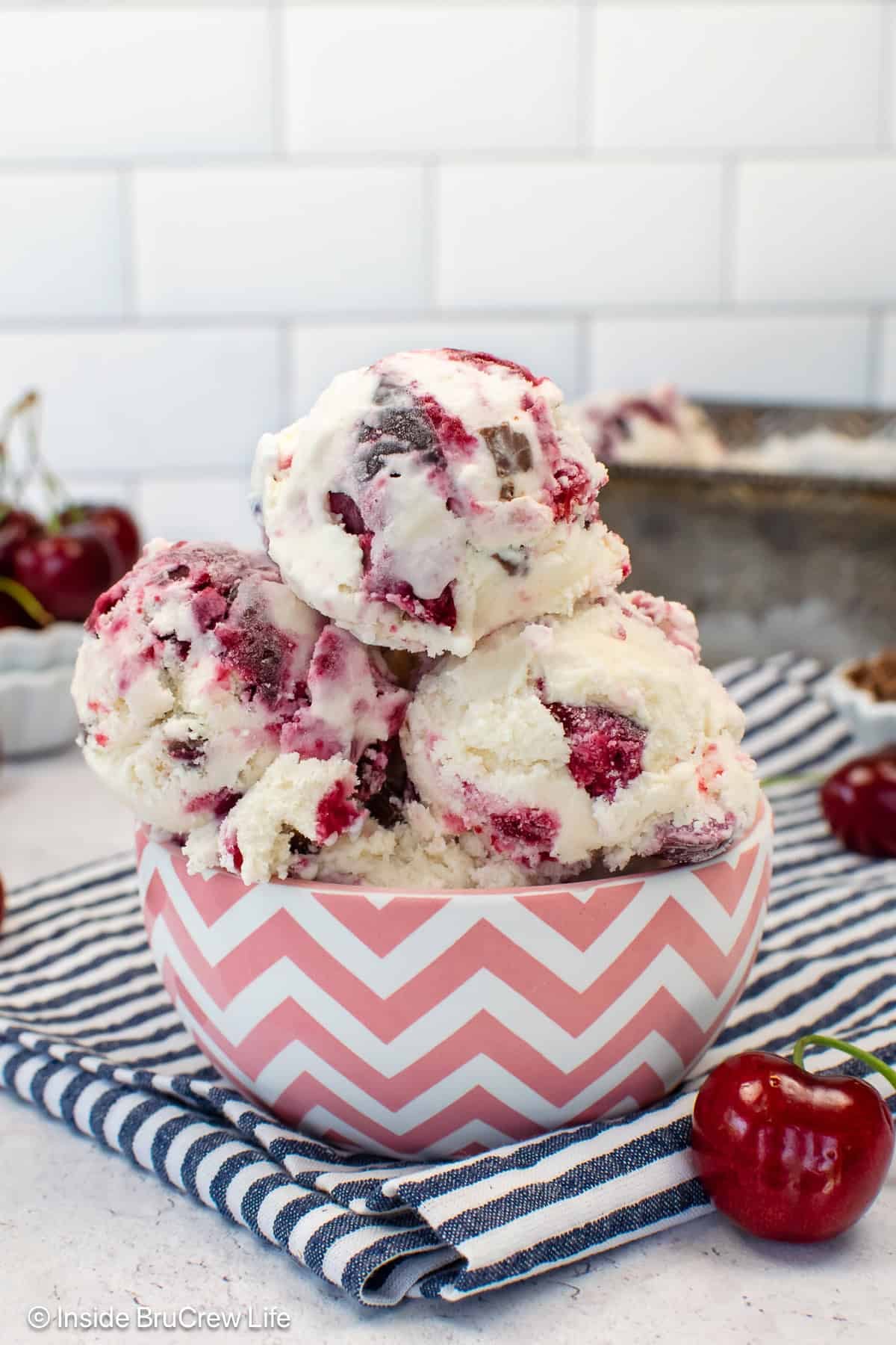 A pink and white bowl filled with scoops of cherry vanilla ice cream.