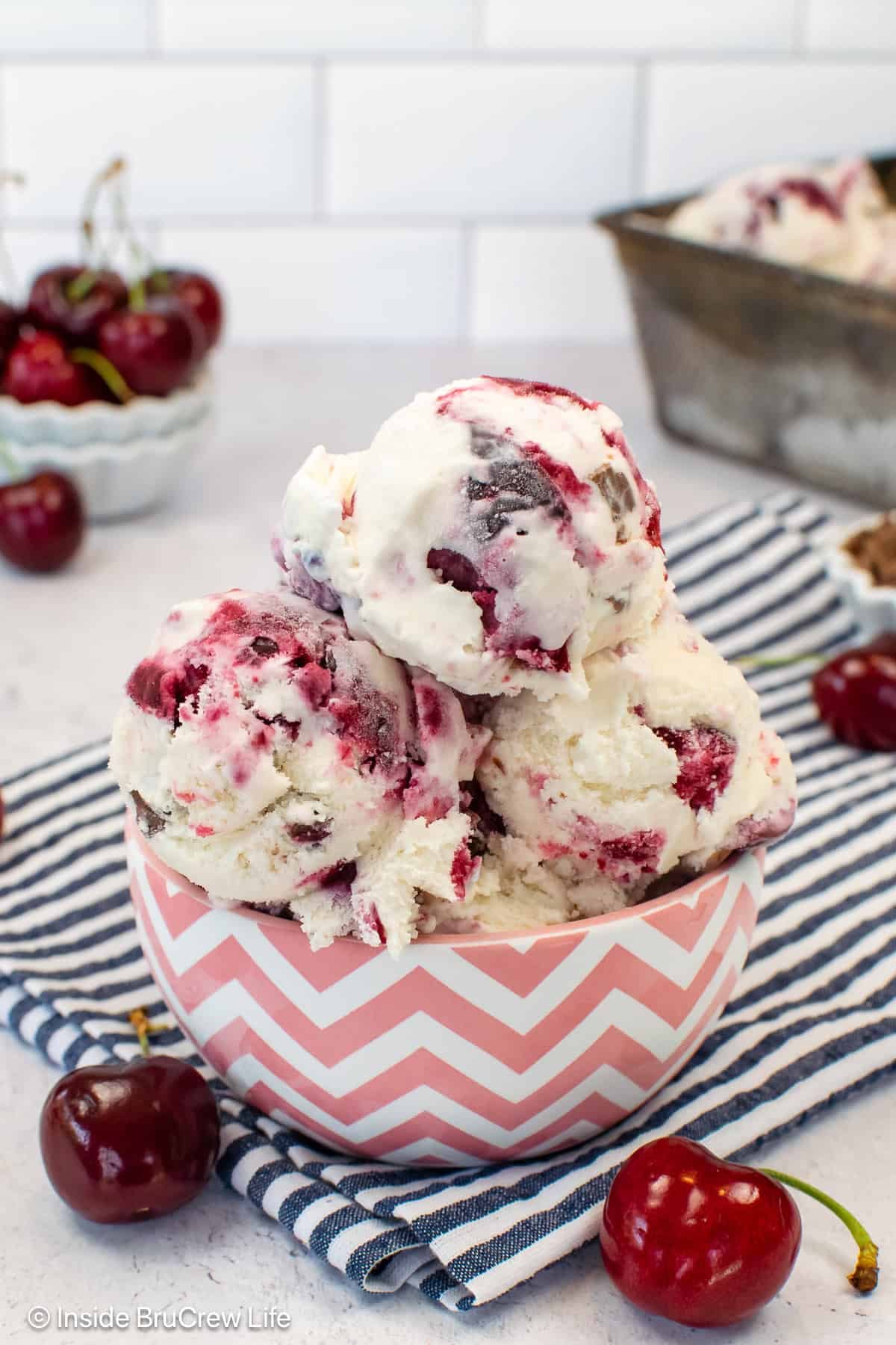 Scoops of cherry vanilla ice cream in a pink and white bowl.