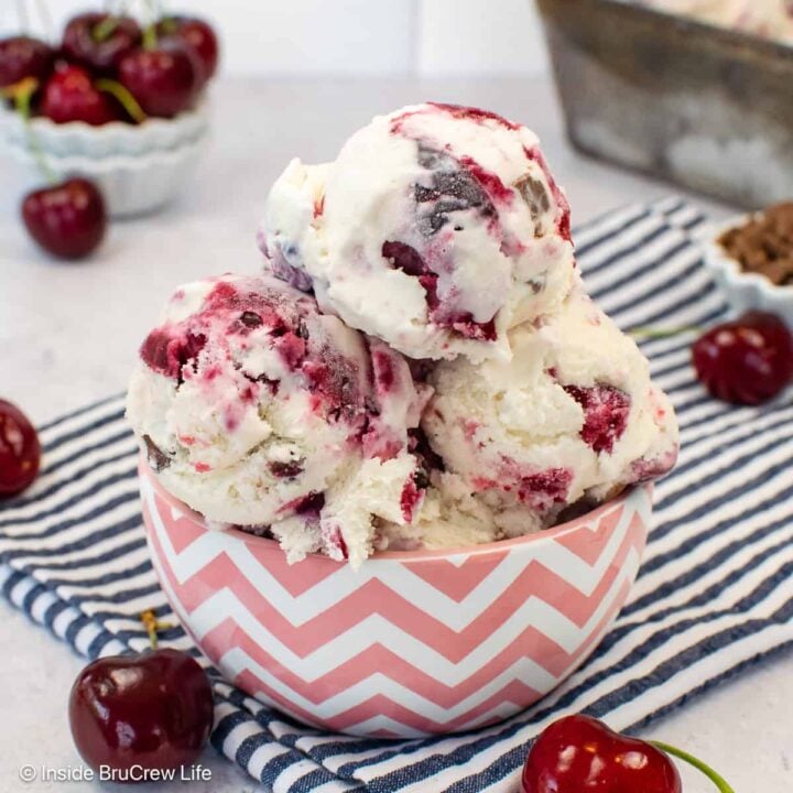 Scoops of cherry vanilla ice cream in a pink and white bowl.
