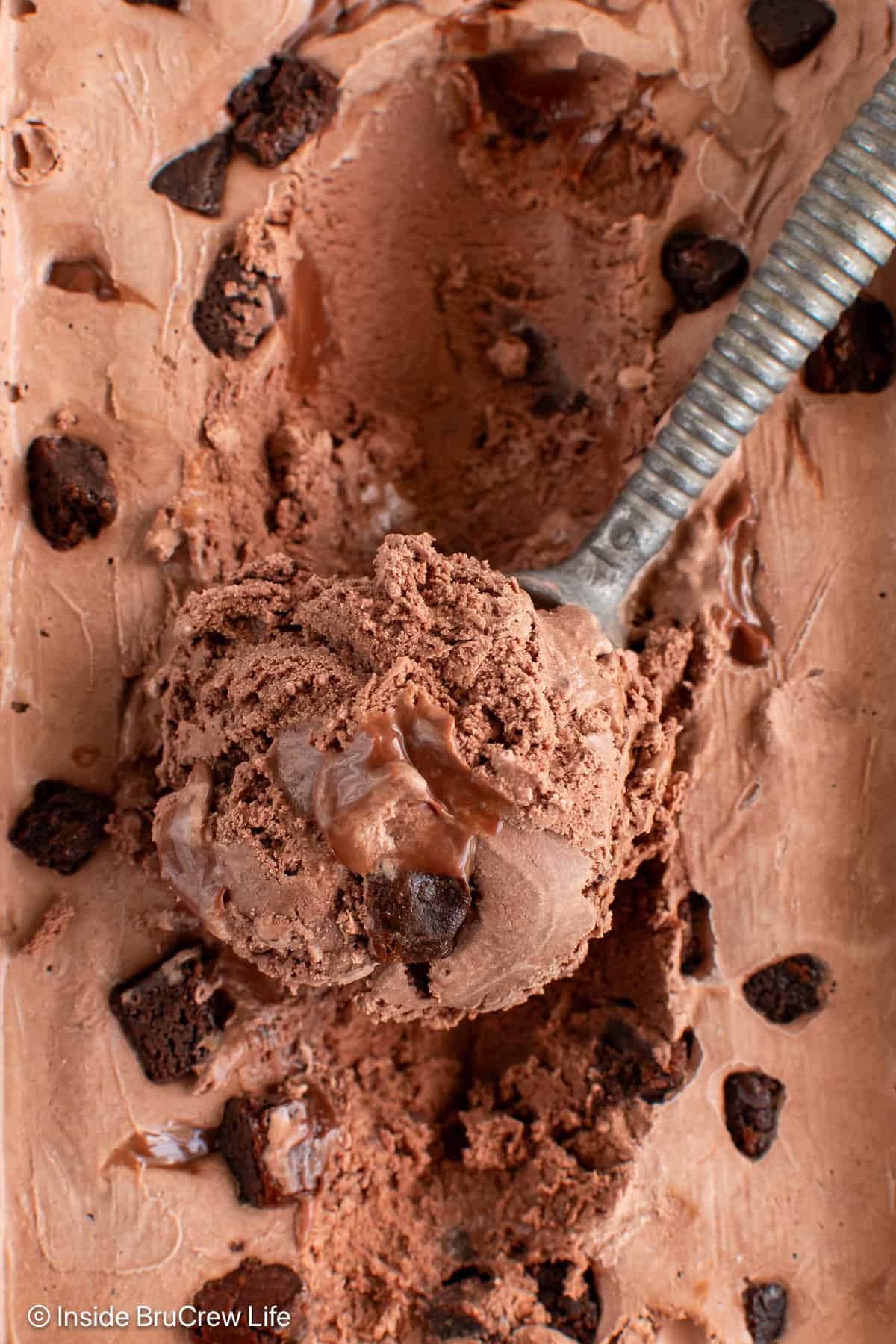 A scoop of fudge brownie ice cream on top of the ice cream container.