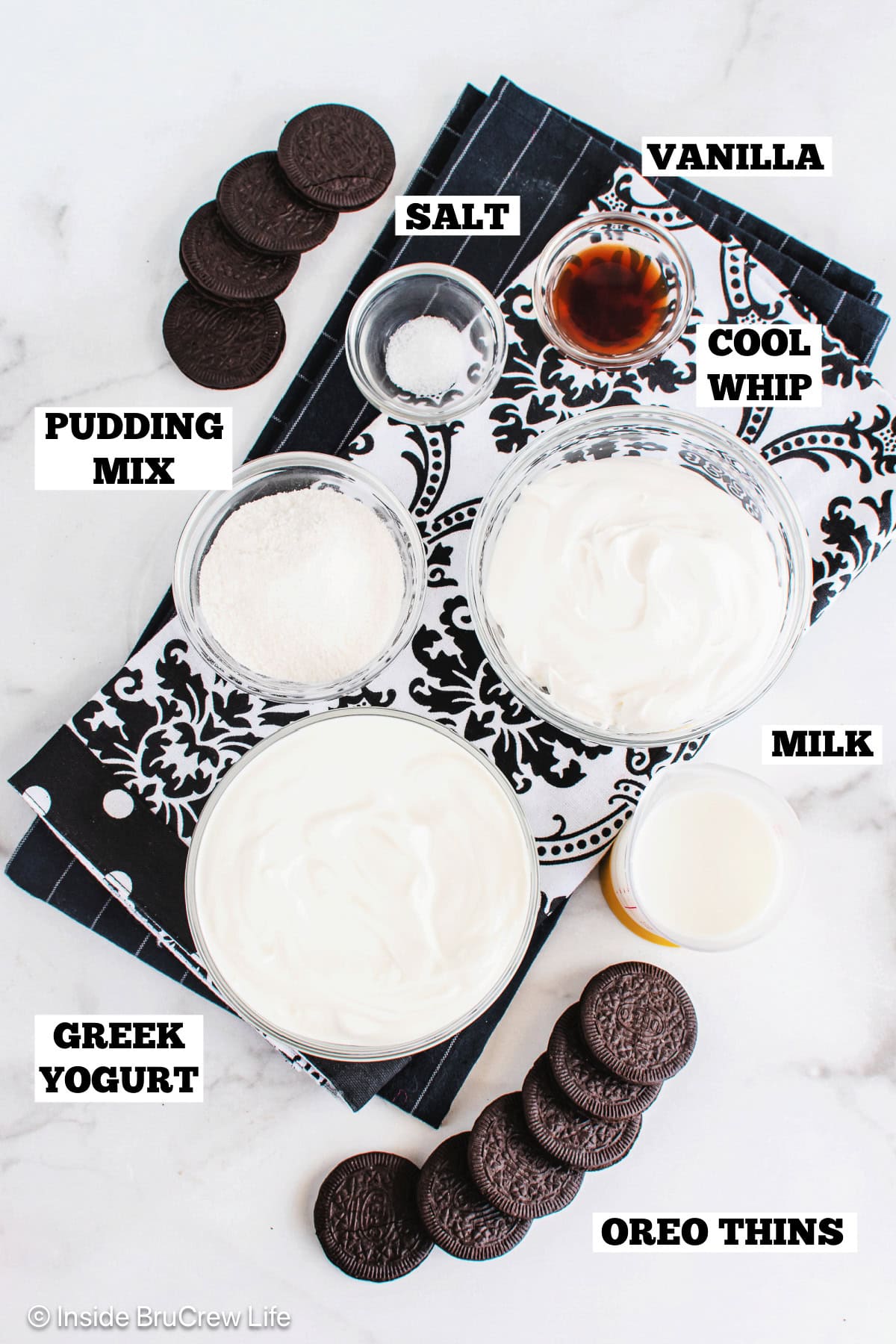 Ingredients for cookies and cream yogurt popsicles on a white board with text labels.