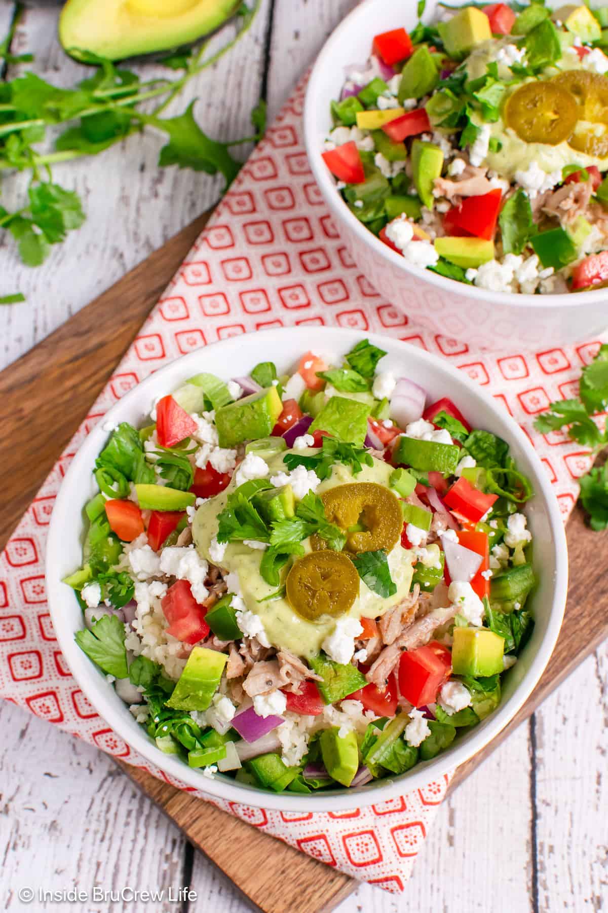 Two burrito bowls filled with pulled pork and fresh toppings.