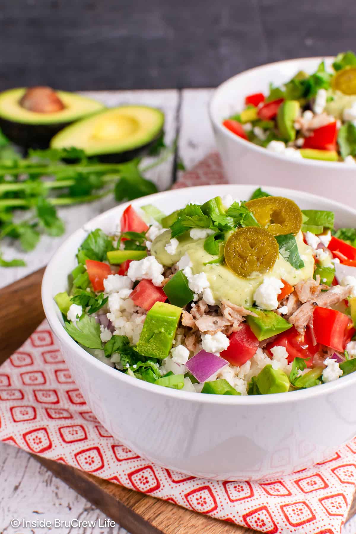 A close up of a pork burrito bowl filled with veggies and dressing.