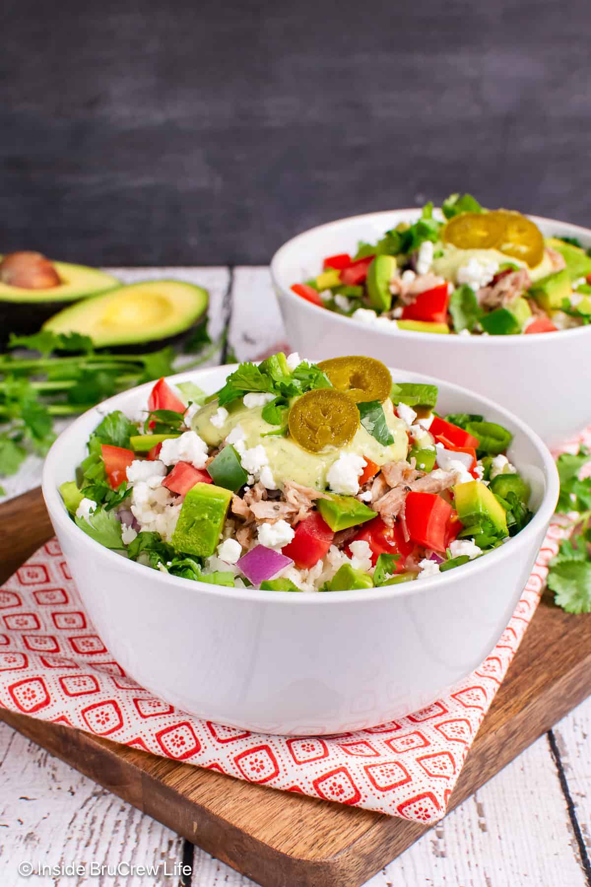 Two pulled pork burrito bowls filled with meat, veggies, and dressing.
