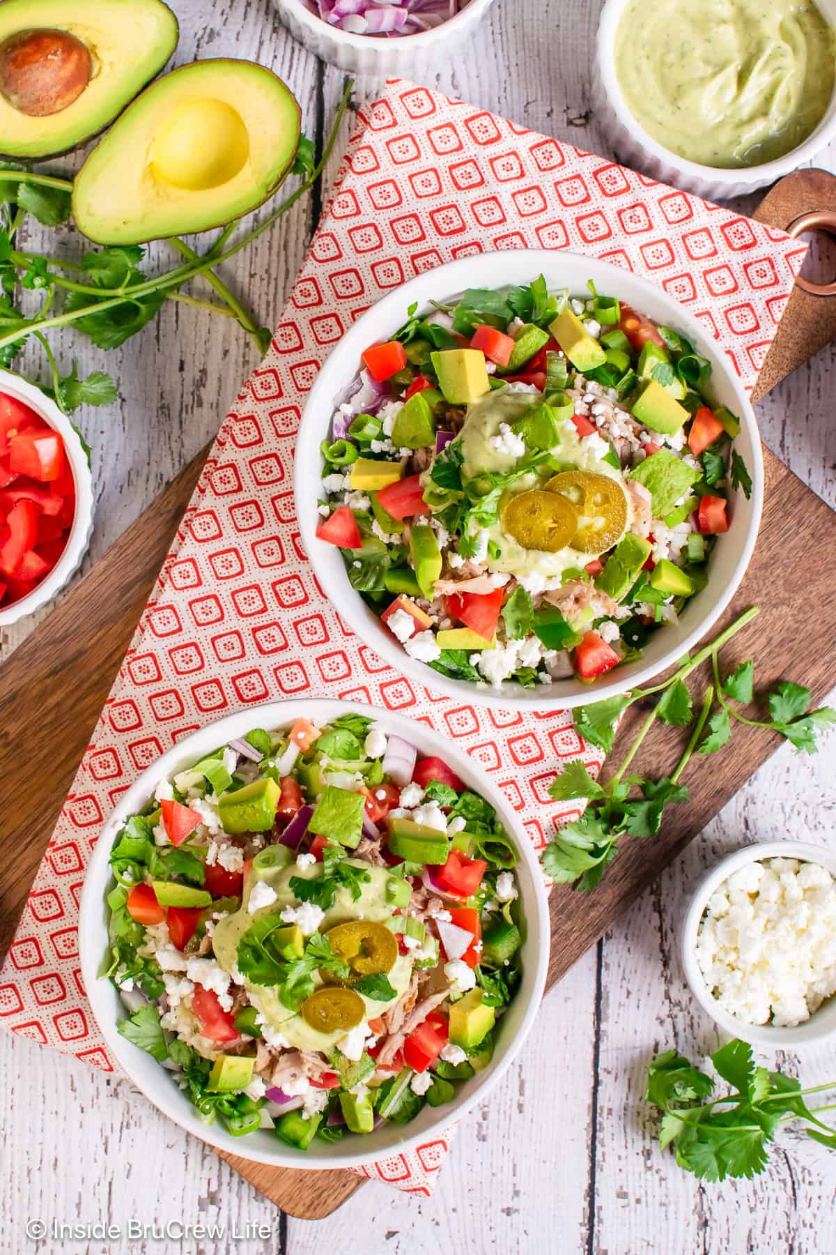 Two burrito bowls filled with pulled pork and fresh toppings.
