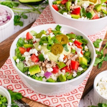 A pork burrito bowl piled with meat, veggies, cheese, and dressing.