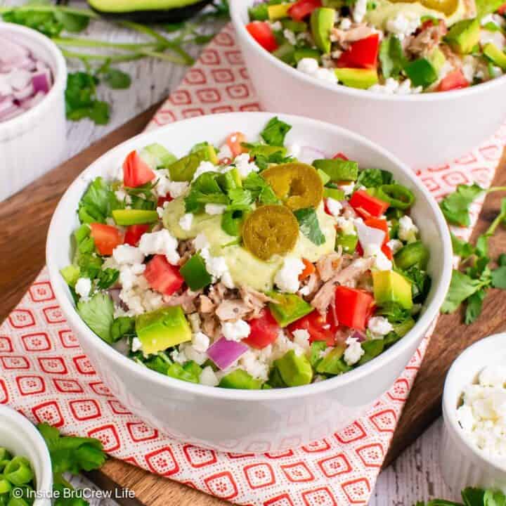 A pork burrito bowl piled with meat, veggies, cheese, and dressing.