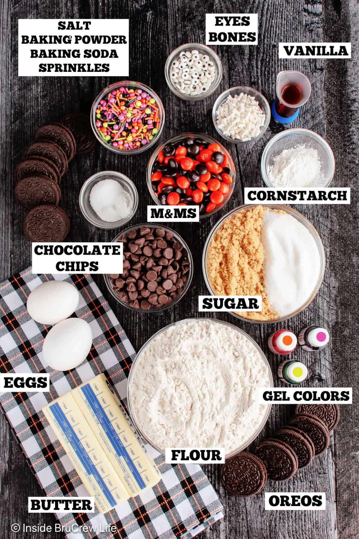 Ingredients for Halloween chocolate chip cookies on a brown board with text labels.