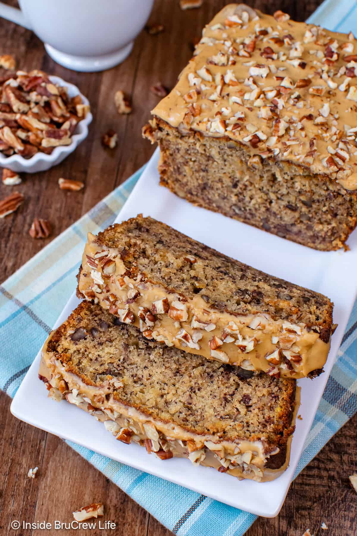 Slices of pecan banana bread with a maple glaze on a white plate.