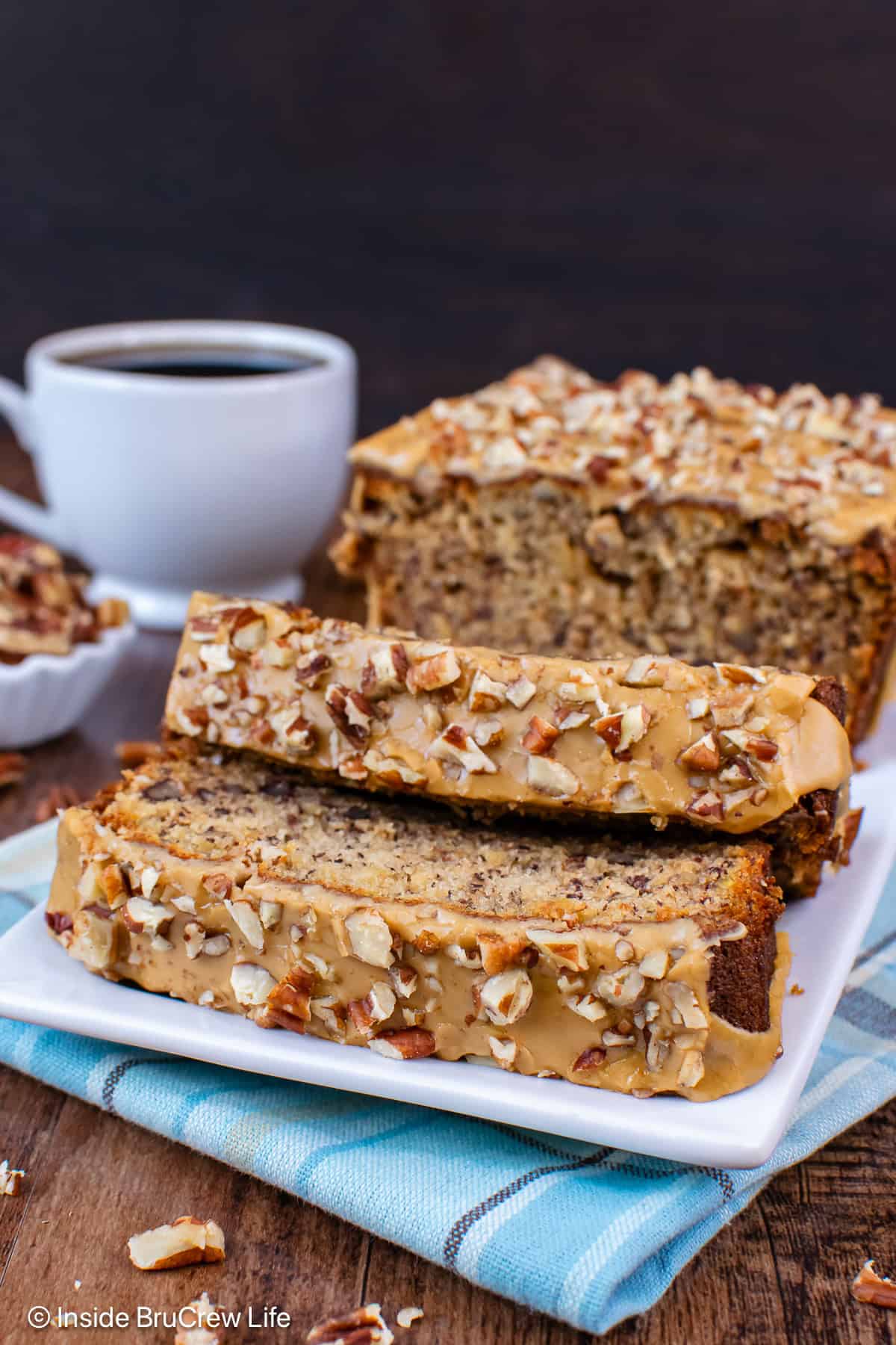 Pecan banana bread with maple glaze sliced and on a white plate.