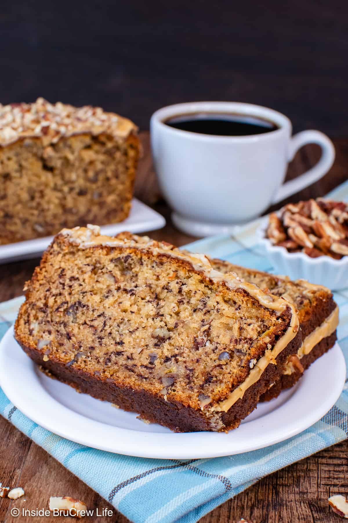 Two slices of a maple pecan banana bread on a white plate.